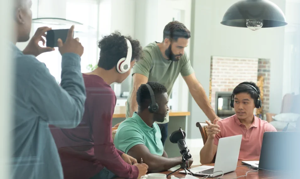 Diverse group of colleagues working together with audio equipment and a laptop.