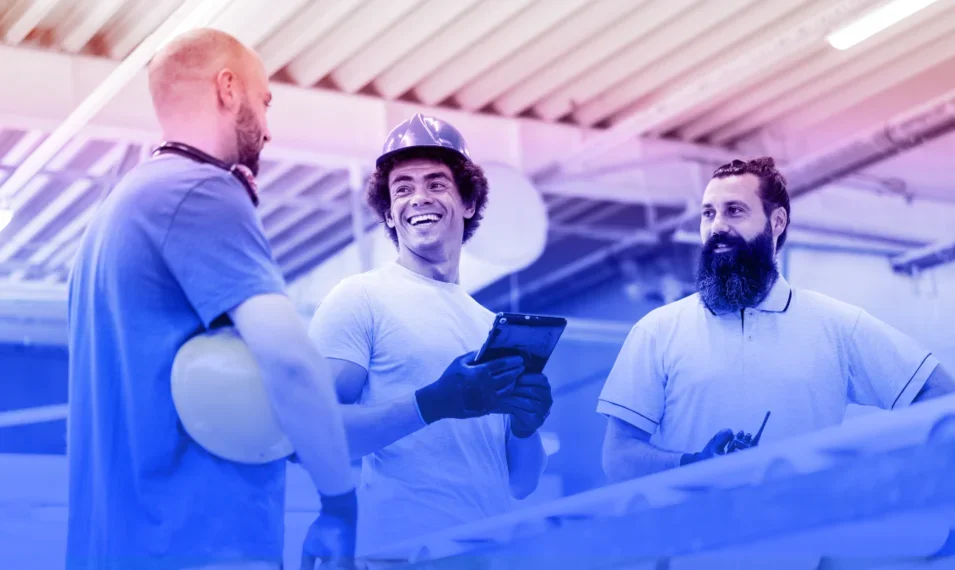 A group of 3 construction workers talking together on site.